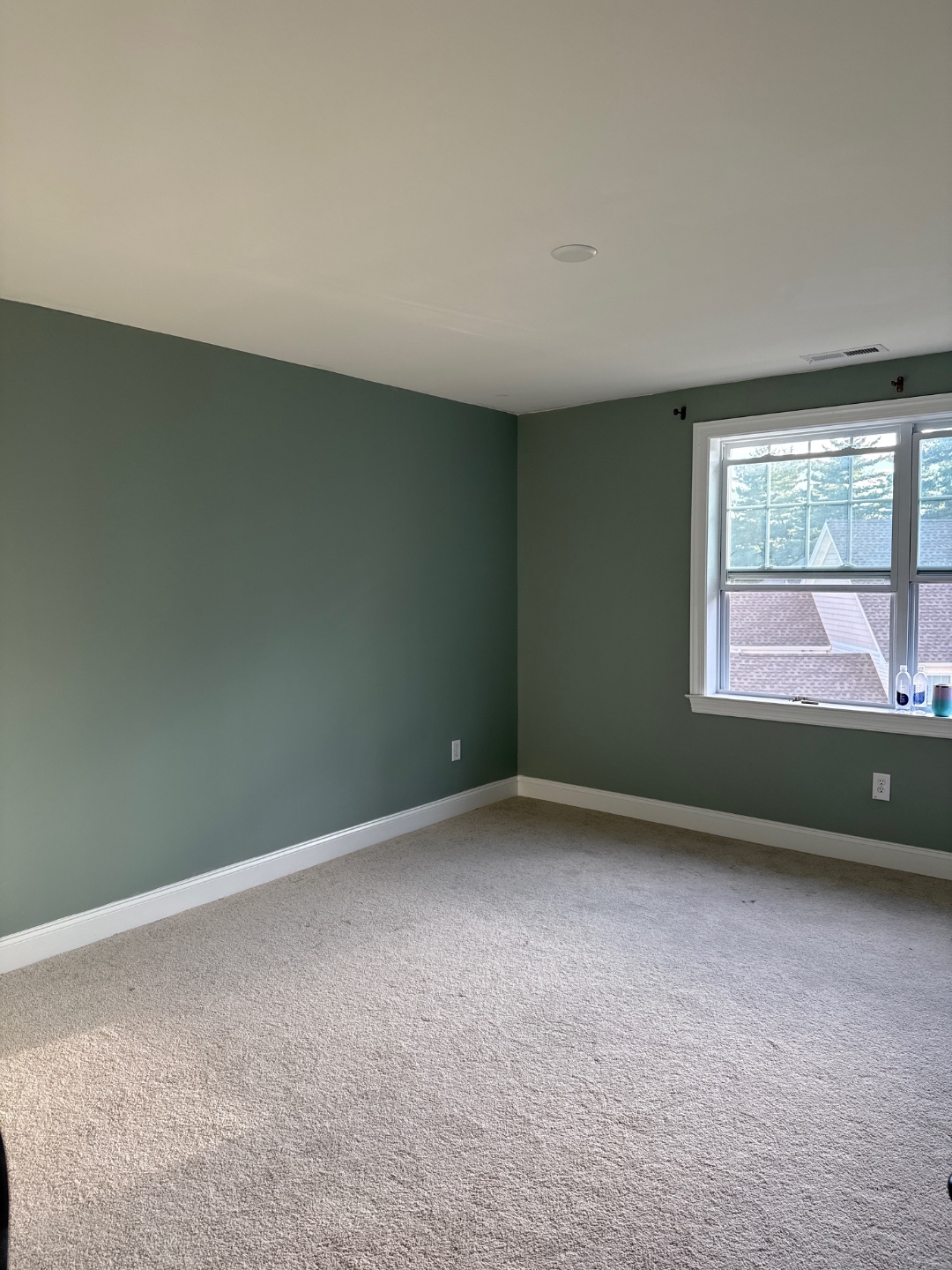 Bedroom freshly painted with sage-green accent wall, furniture removed for the job